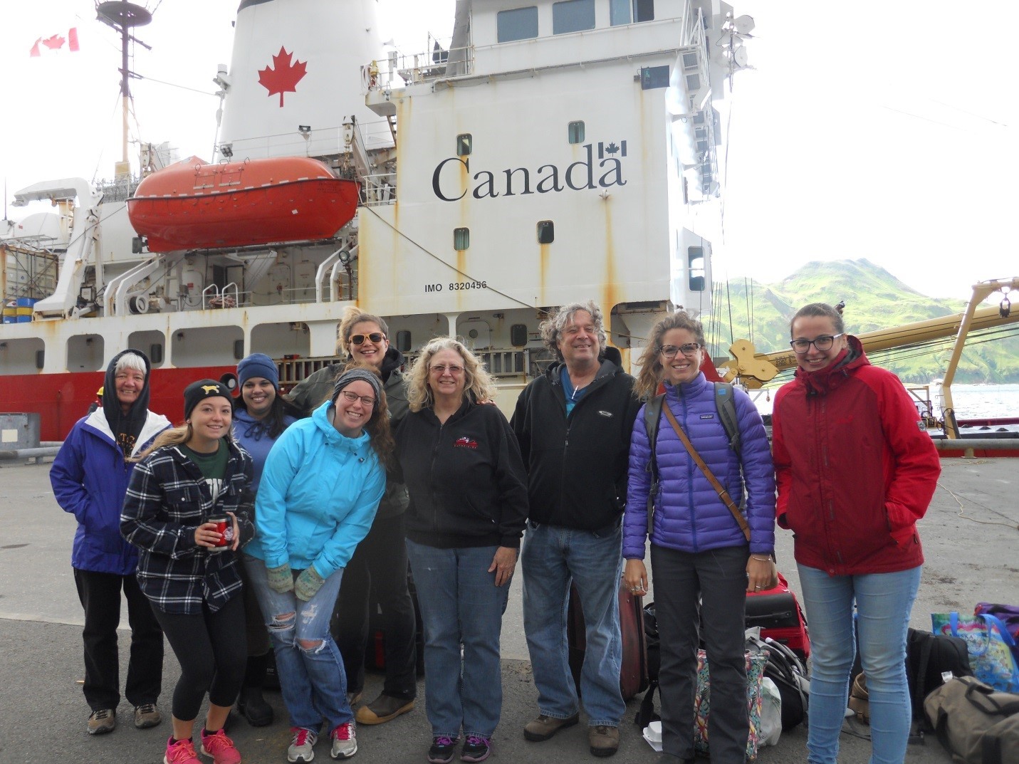 Student Sophie Caradine-Taber standing with researchers at dockside in front of the Sir Wilfrid Laurier icebreaker
