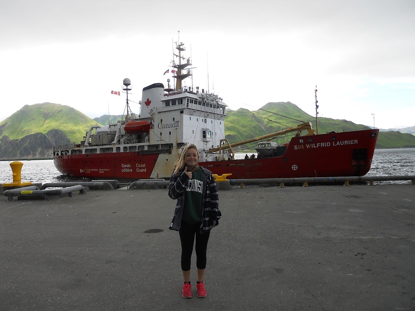 photo of student Sophie Caradine-Tauber standing at dockside in front of the Sir Wilfrid Laurier icebreaker