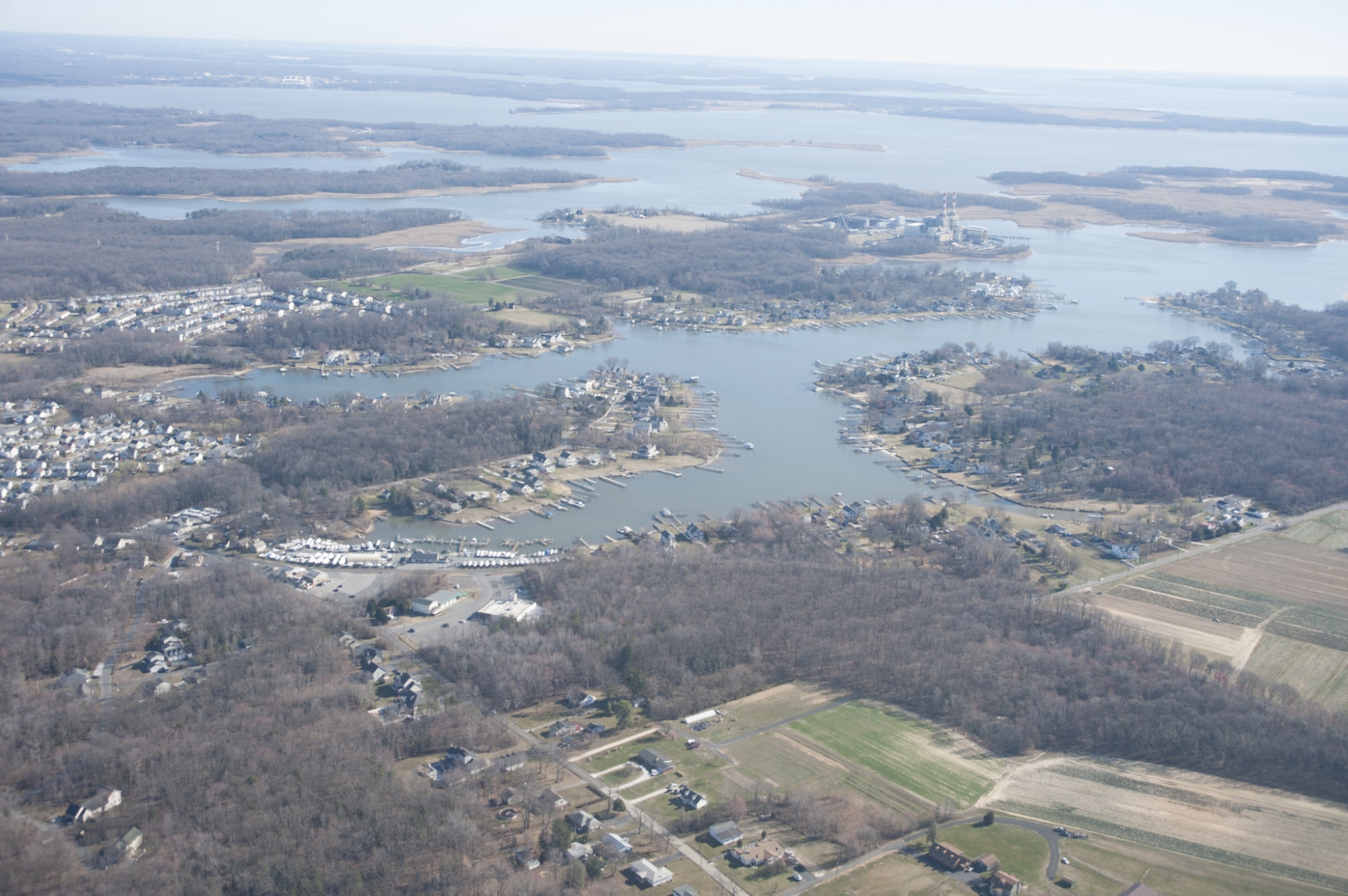 An aerial image of a portion of the Chesapeake Bay surrounded by houses, piers, trees, and farmland