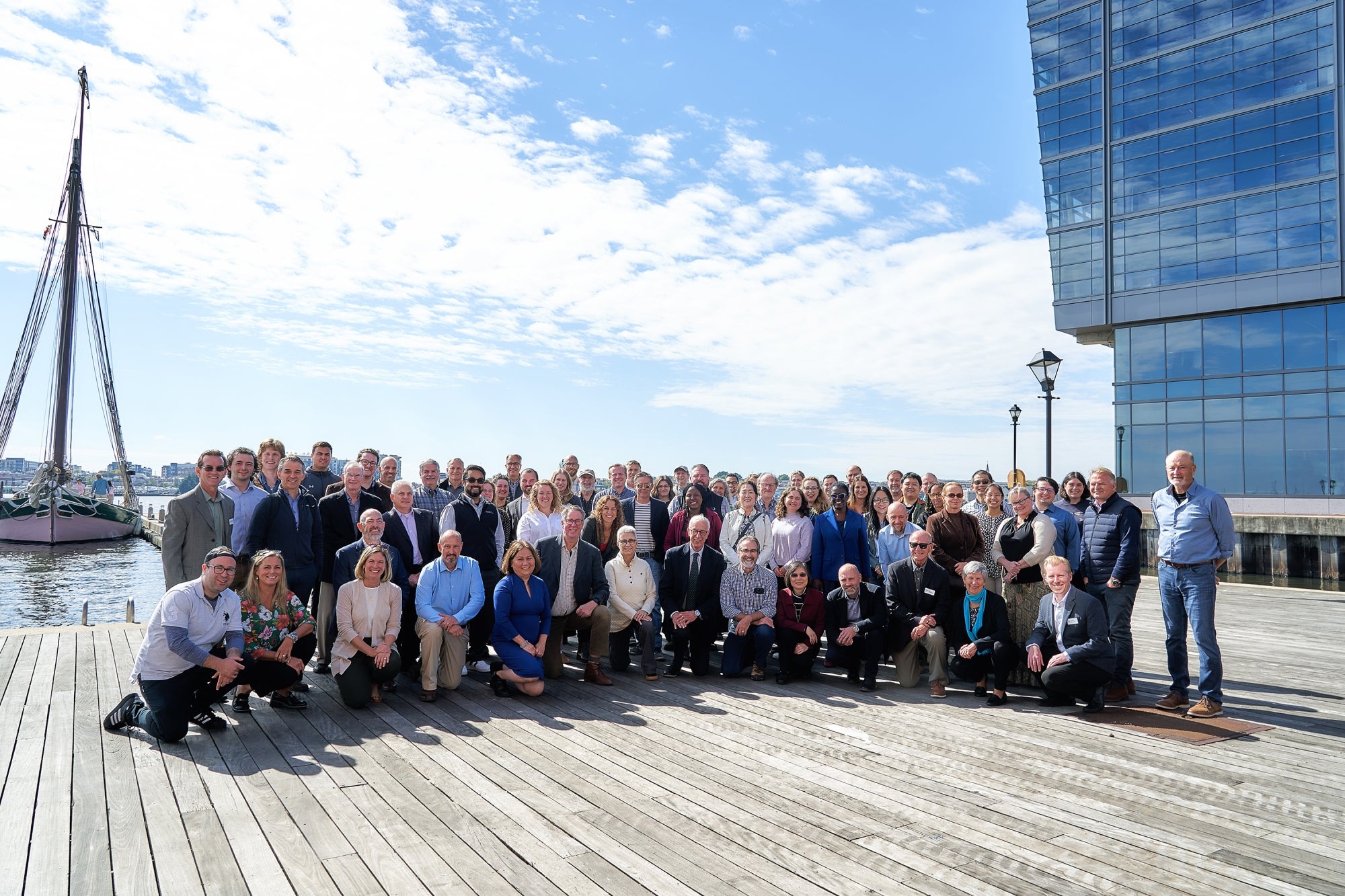 A group of people pose together for a photo on a wooden pier near water