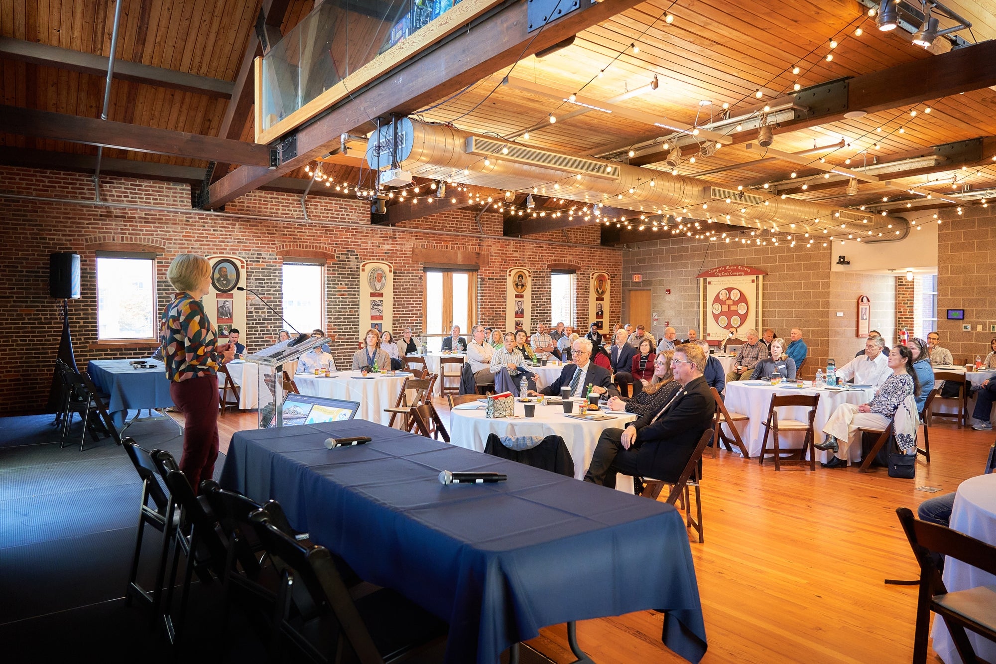 A woman presents to a group of people seated at round tables