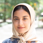 Headshot of a woman with a tan headscarf and black hair