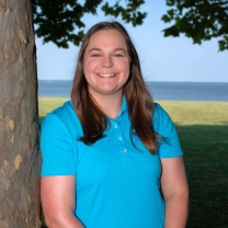 Erika Koontz smiles under a tree near marshes.