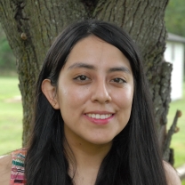 Paulina stands in front of a tree, smiling.