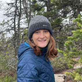 Julia Smeltzer with a winter hat and blue coat in a forest