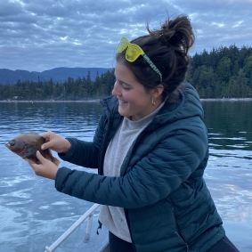 Brown haired woman in blue coat holding a fish