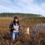 A young woman stands in knee-high marsh grasses near water holding a net