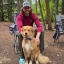 Michael Macon sits in a camp chair and poses with a dog in the woods