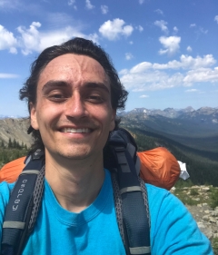 Michael Kalinowski wears a hiking backpack and poses for a selfie