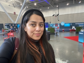 Paulina stands in a conference hall with tables behind her.